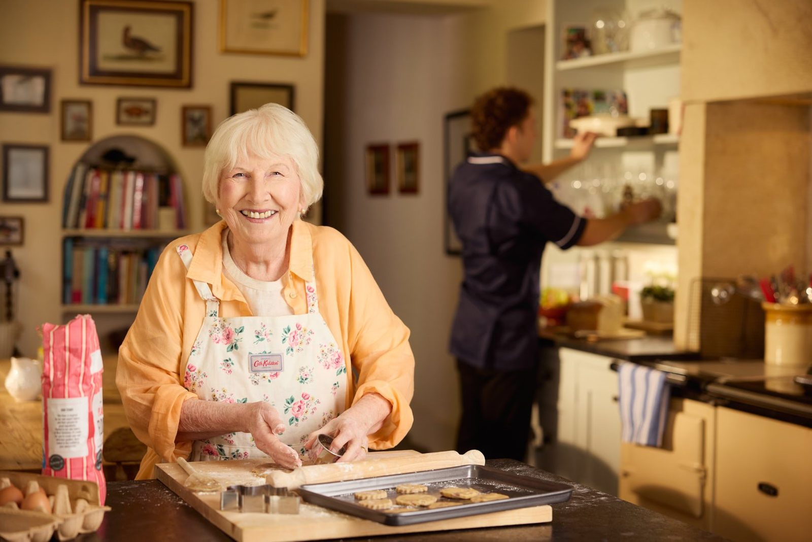 Bluebird Care: a woman baking in her kitchen with a carer behind her