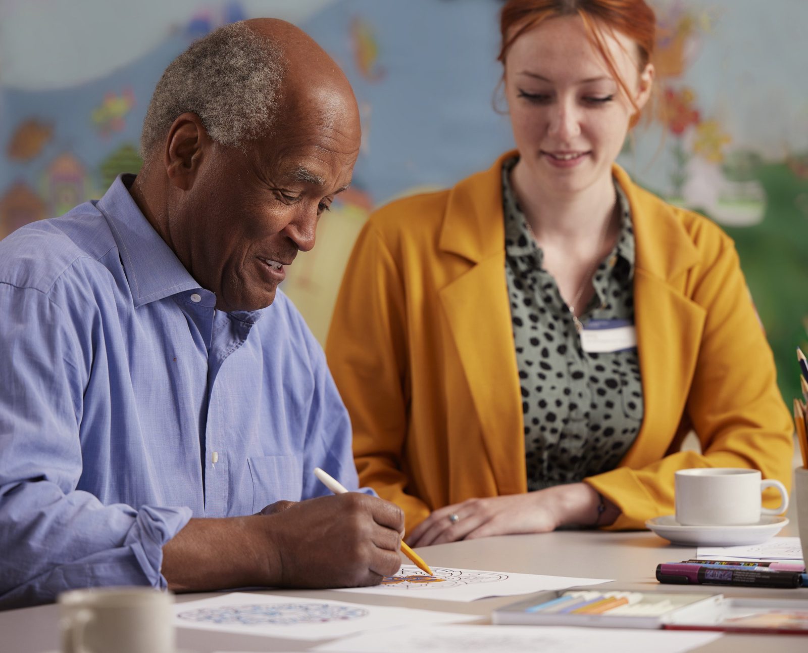 Elizabeth Finn Homes: a resident and a team member in a yellow jacket drawing together at a table