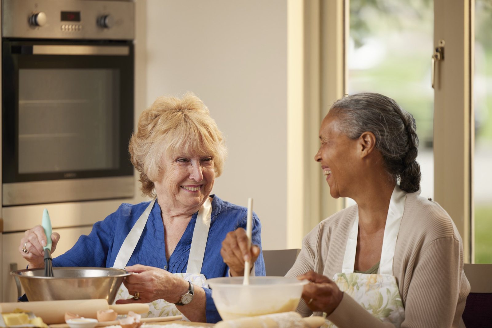 Two women baking together in a care home kitchen