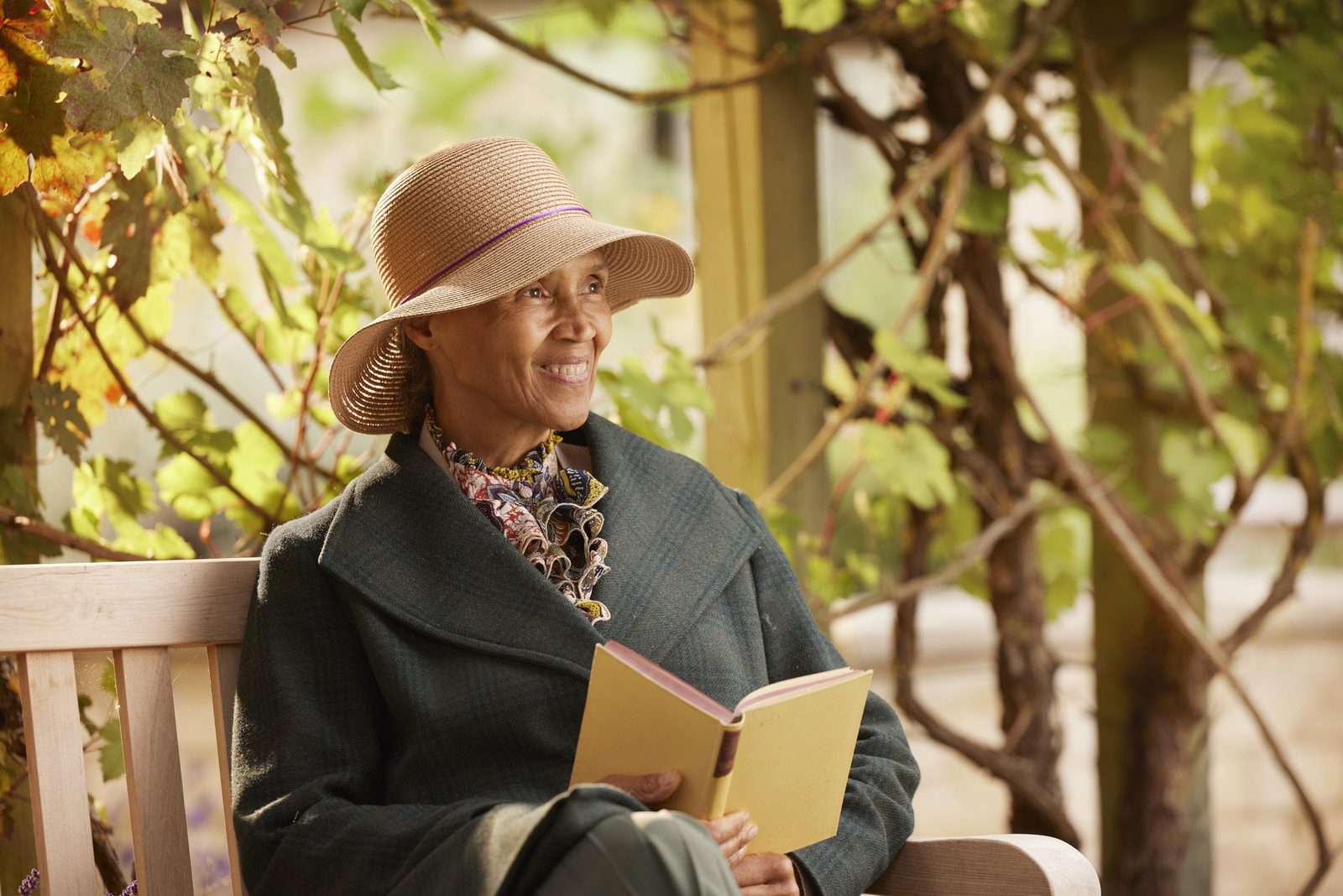 Elizabeth Finn Homes: a resident in a sun hat reading a book on a garden bench