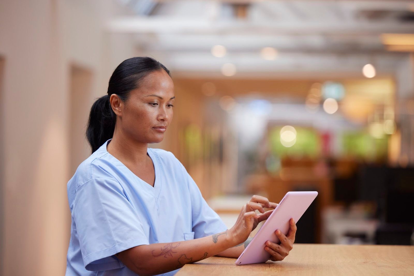 A nurse using a tablet in a bright lounge