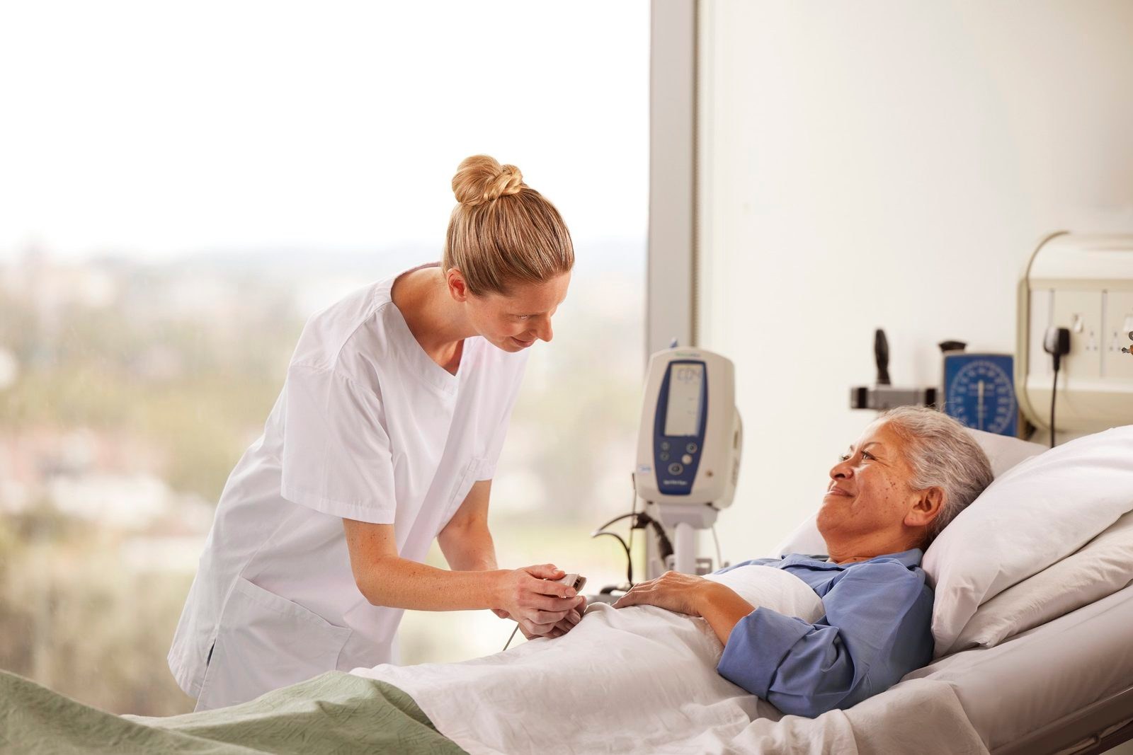 Florence: a nurse checking on a smiling patient in a hospital bed