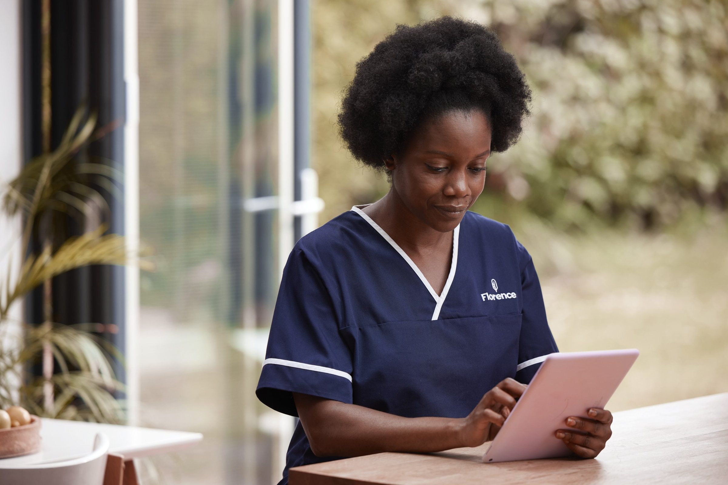 A Florence nurse looking at a tablet by a window